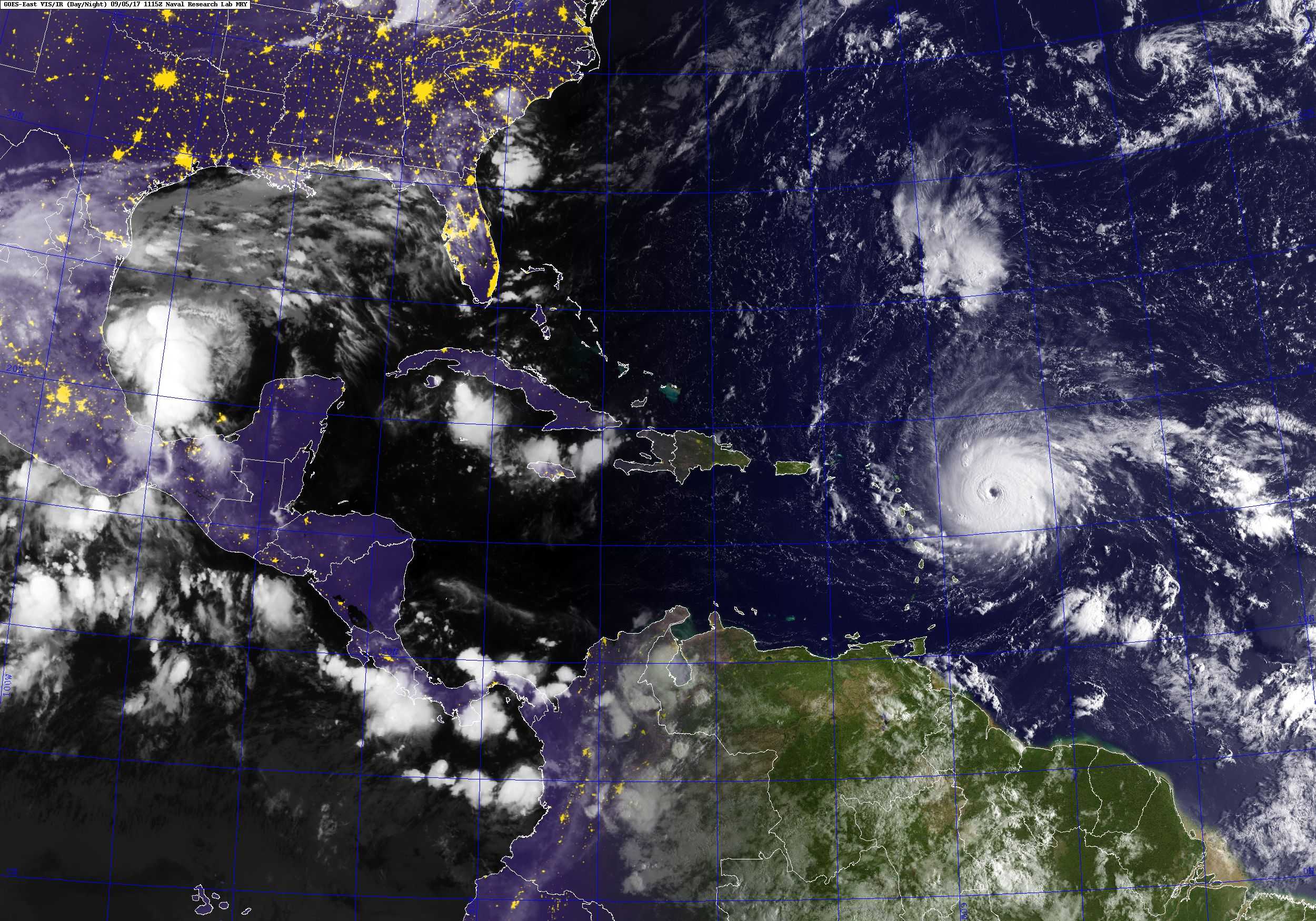 Satellite view of a large hurricane with a visible eye over the Atlantic, east of the Caribbean, with coastlines and city lights.